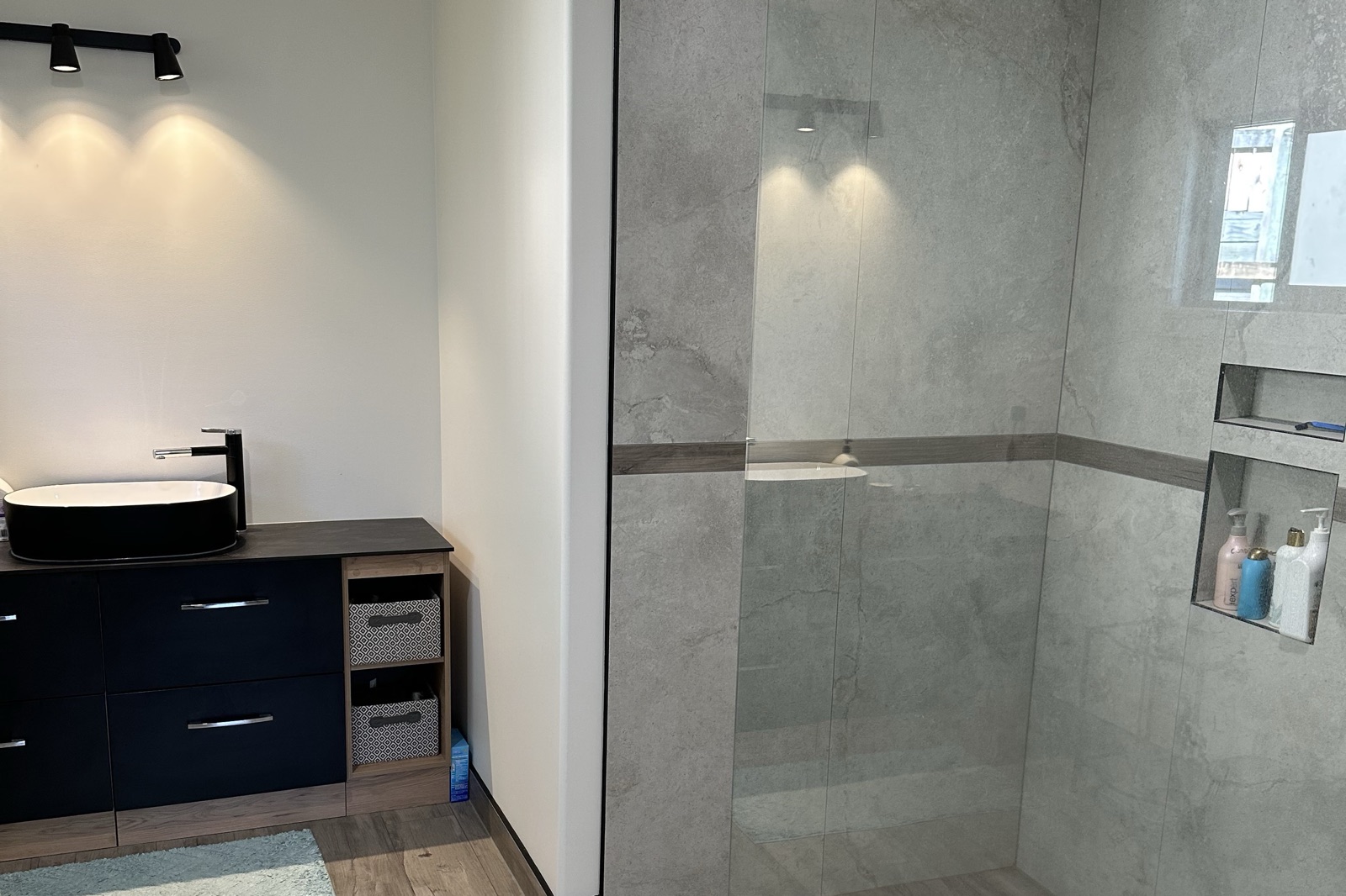 Walk-in tiled shower with a glass screen beside a vessel basin vanity