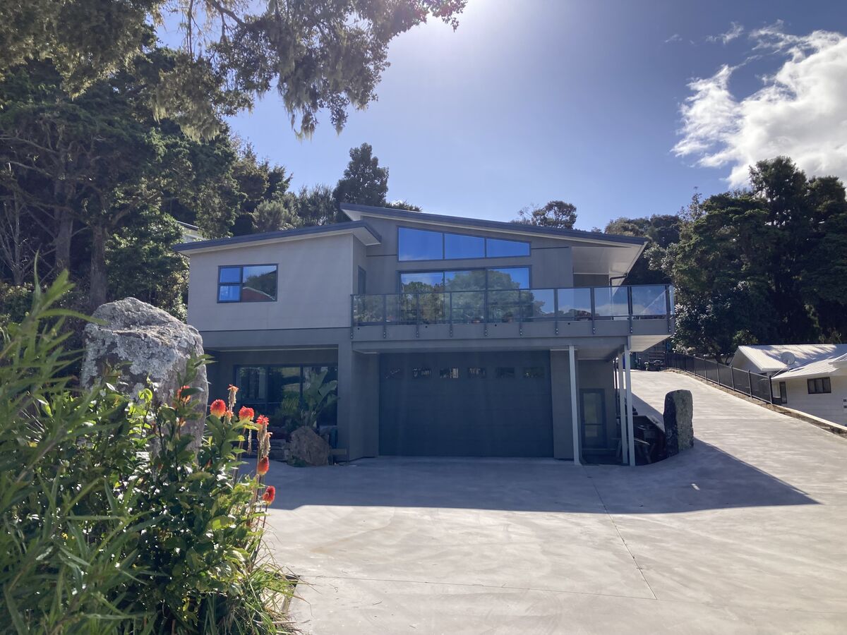 Finished two-storey home with a glass balcony above a new concrete drive